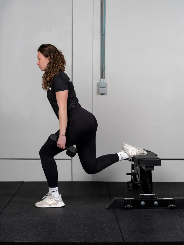 Een sporter doet lunges met halters
